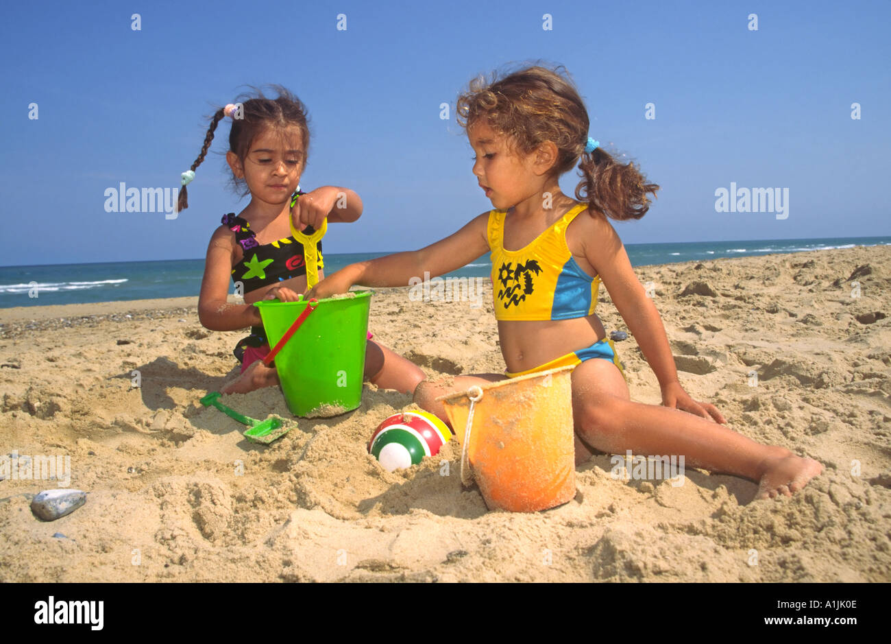 Two Young Girls Playing with Bucket and Spade on Beach Stock Photo - Alamy