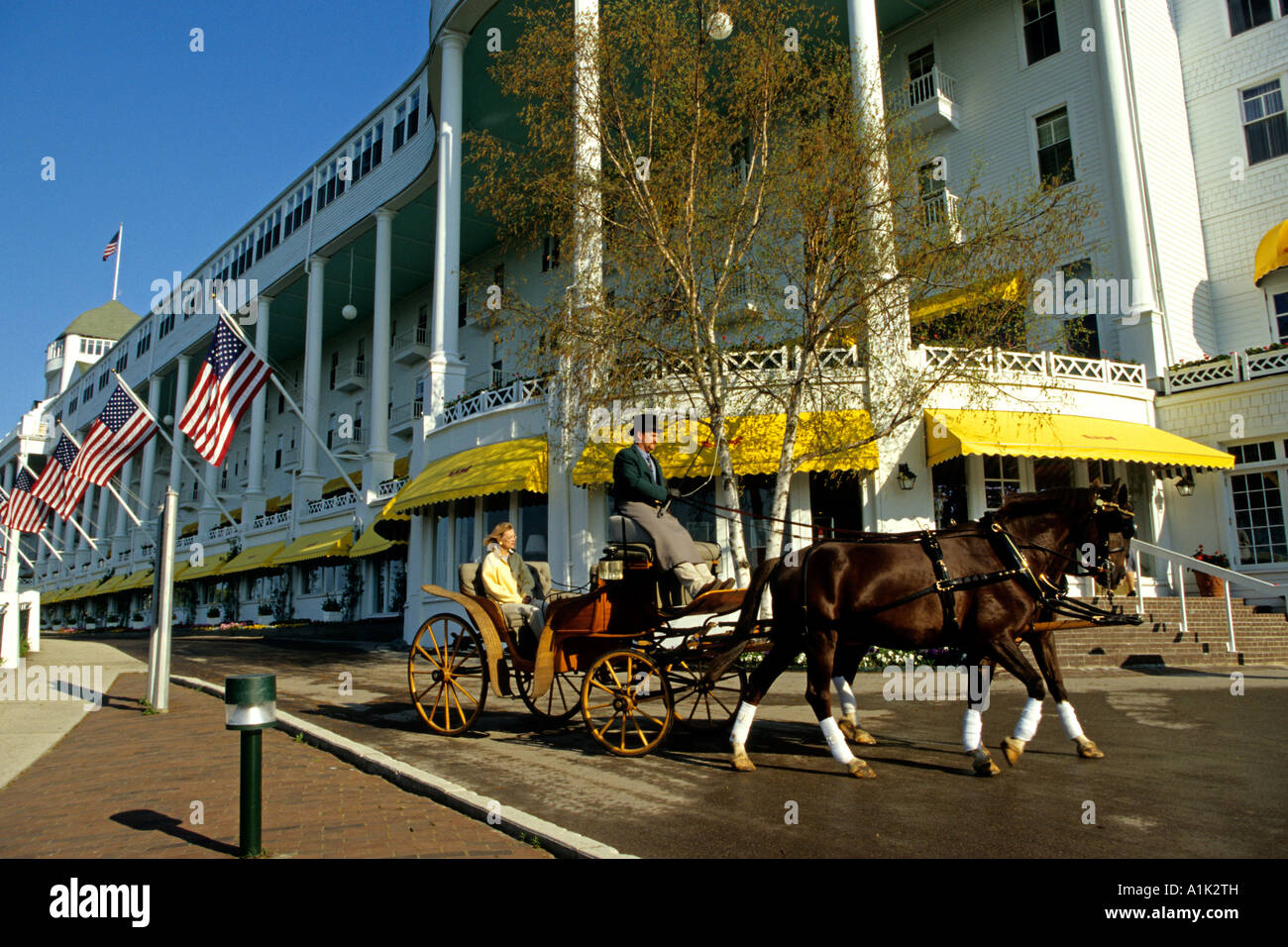 A horsedrawn carriage departs The Grand Hotel on Mackinac Island in the upper peninsula of Michigan USA Stock Photo