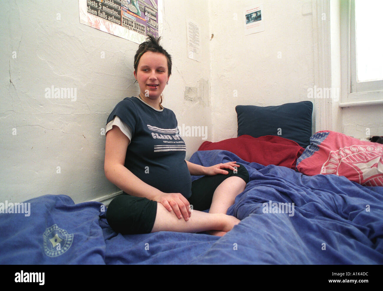 Young pregnant woman sitting on bed. Stock Photo