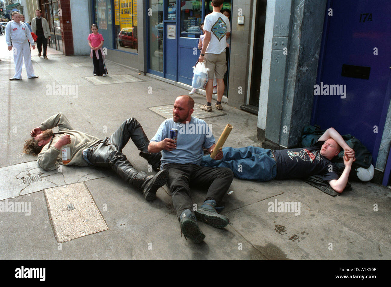Drunken men falling over rolling on the pavement drunk. Stock Photo