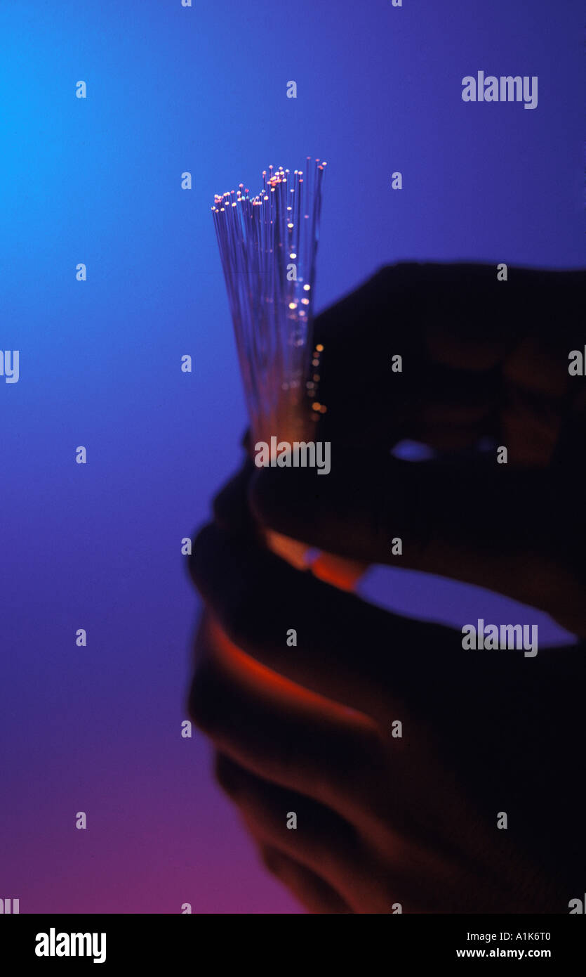 silhouetted hand holding multi colored fiber optic strands Stock Photo