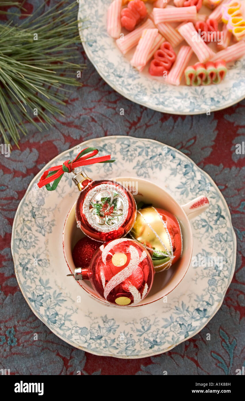 Vintage Christmas ornaments in a teacup with antique china on a brocade background. Stock Photo