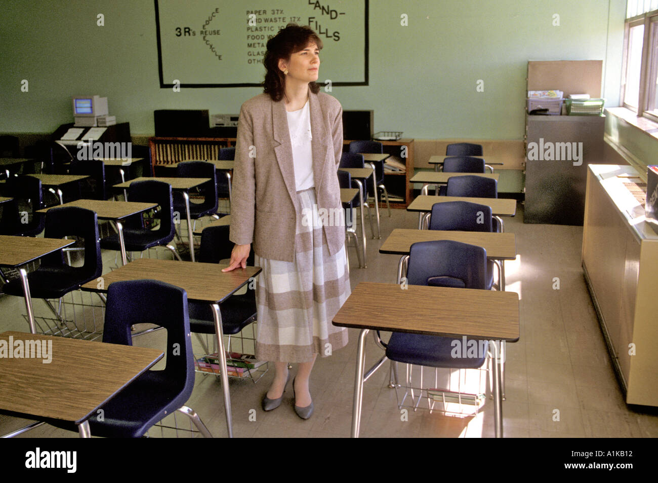 Teacher stands in an empty classroom in a pensive moment Stock Photo