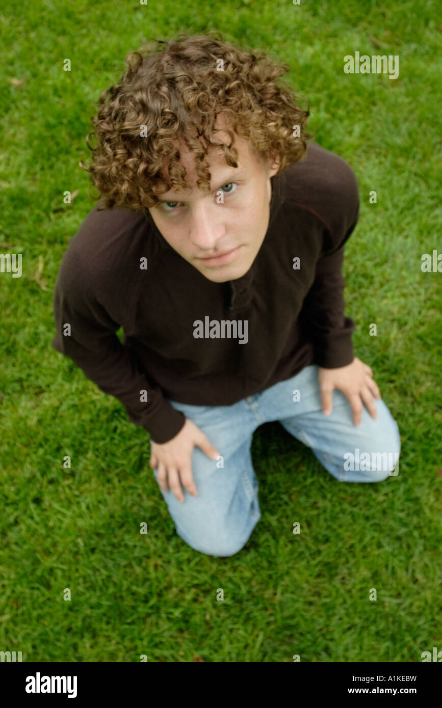 Young man outdoors kneeling on lawn Stock Photo - Alamy