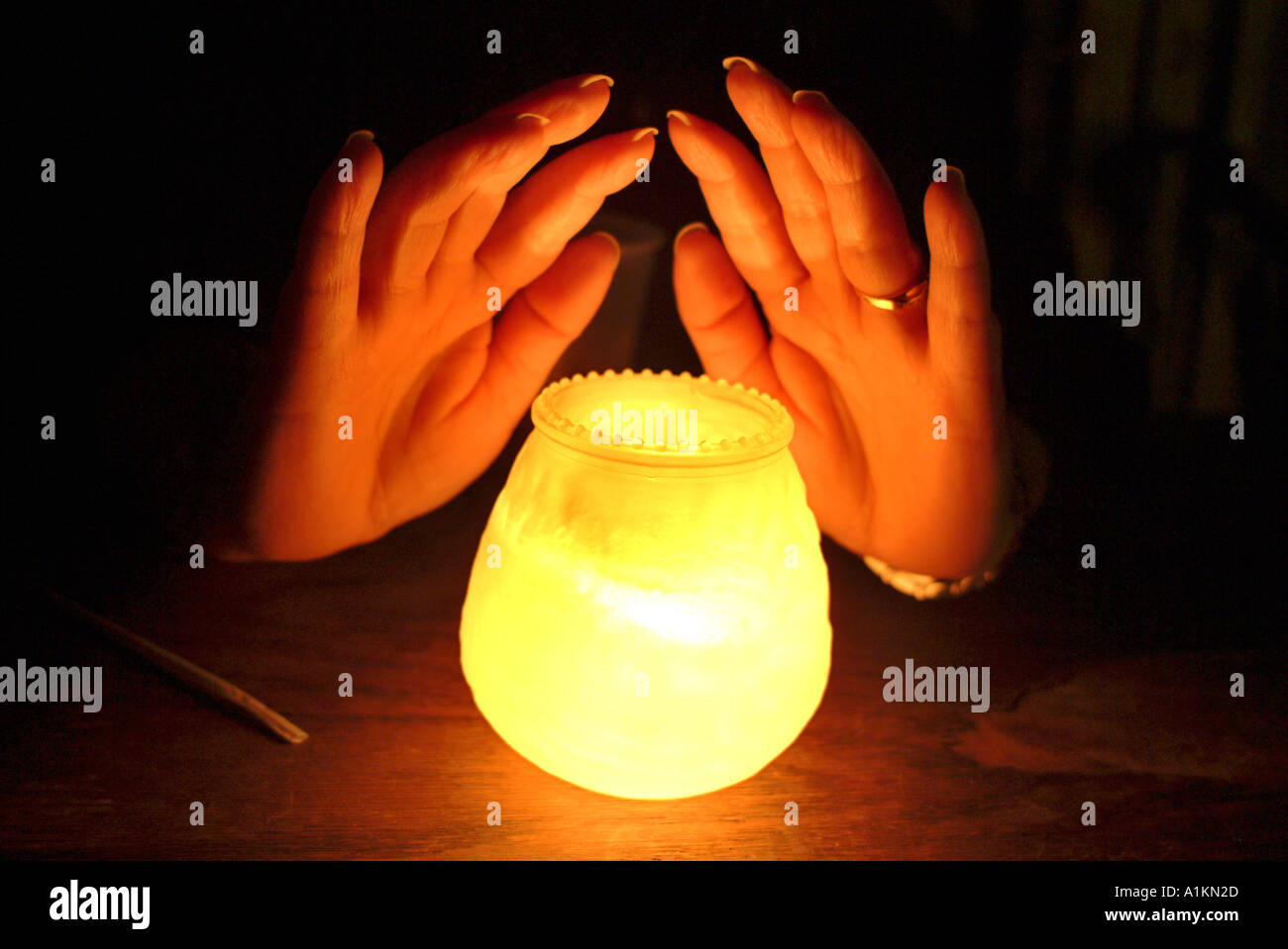 Female hands wrapped around candle Stock Photo
