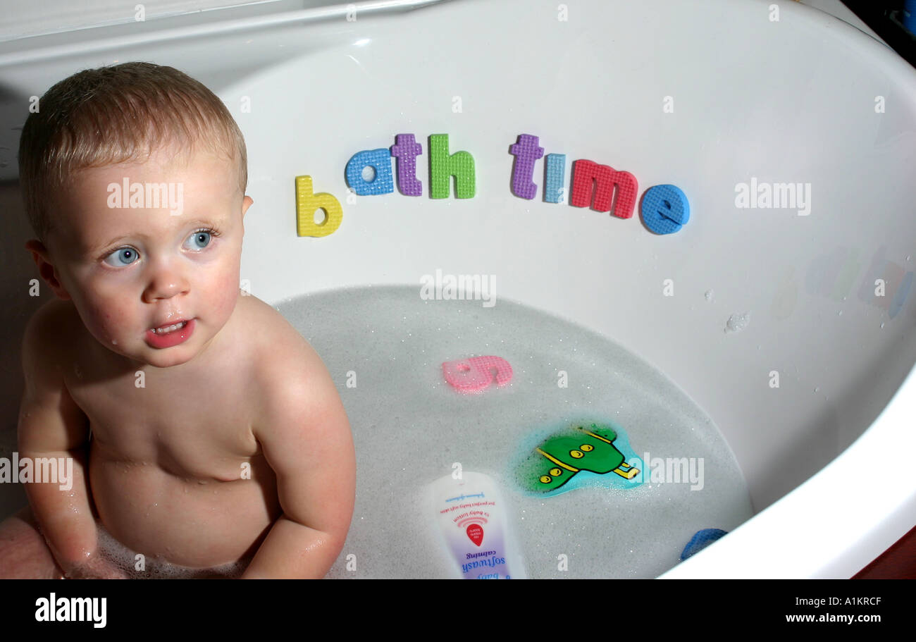 Baby sitting in bath with letters implying a higher level of