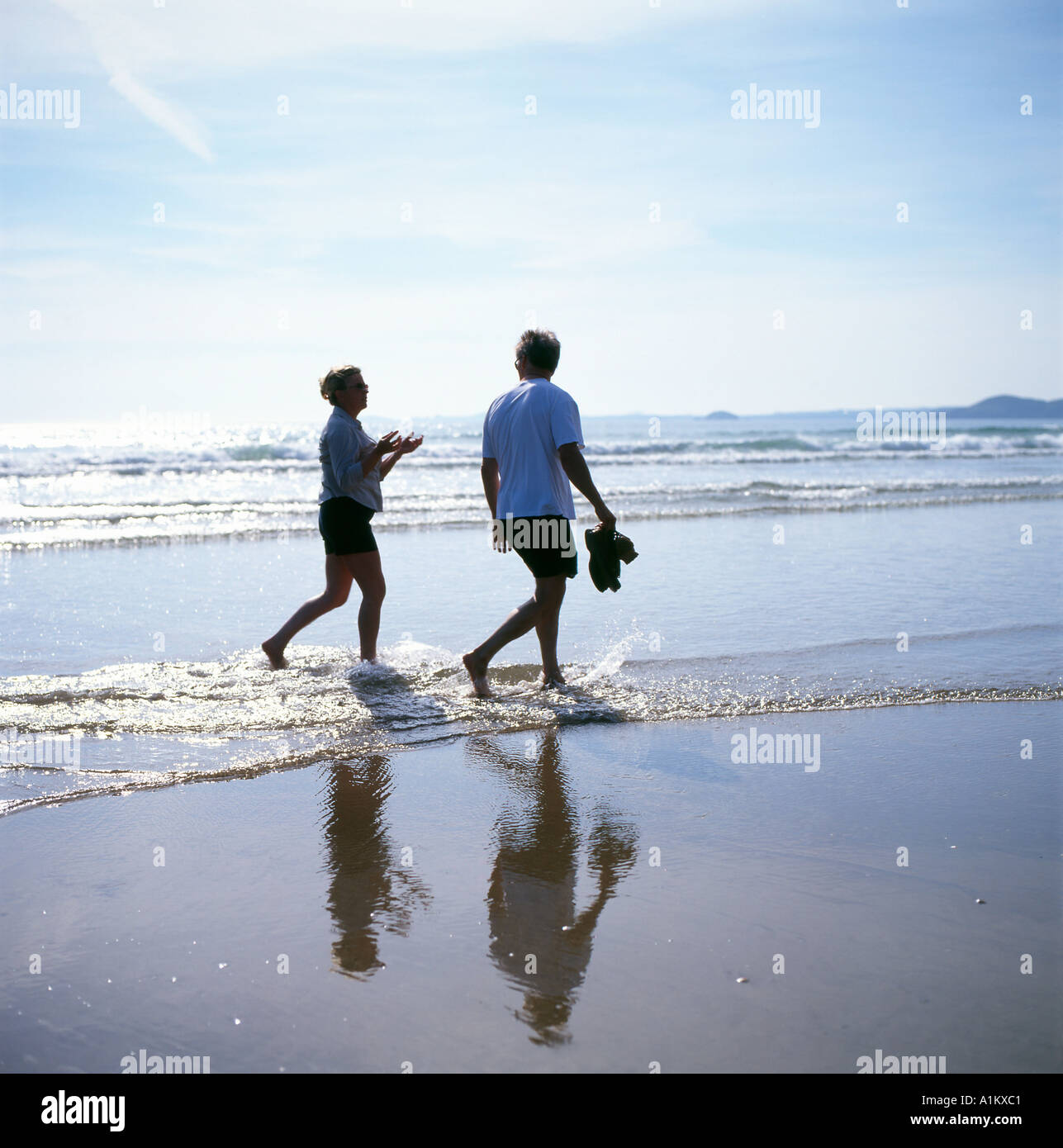 A senior couple walking along the beach Pembrokeshire Wales UK Stock Photo