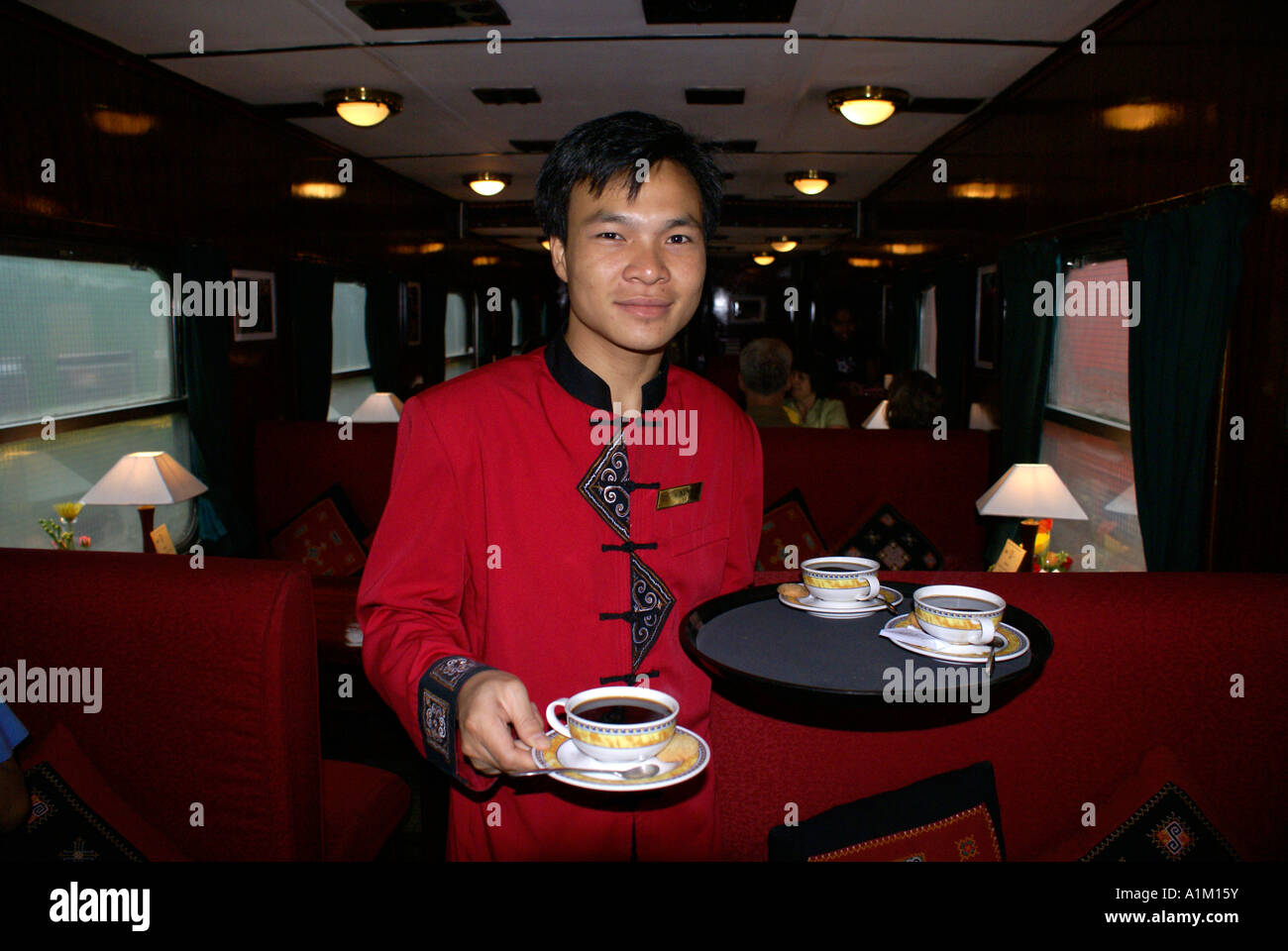 Waiter serving coffee on the Victoria Express train on the route between Hanoi and Lao Cai, Vietnam Stock Photo