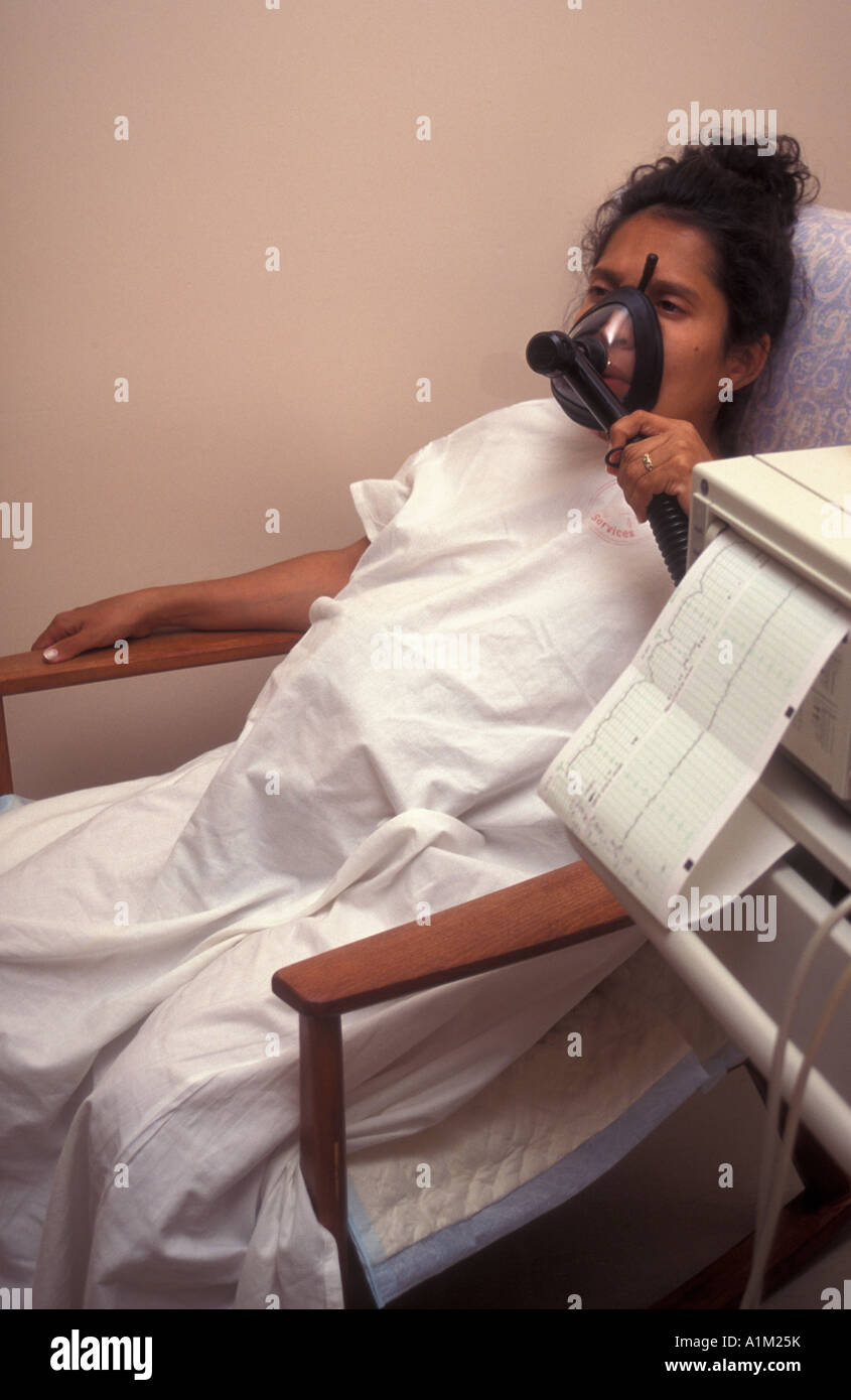 Pregnant Hispanic woman in labour in hospital using gas and air mask for pain relief Stock Photo