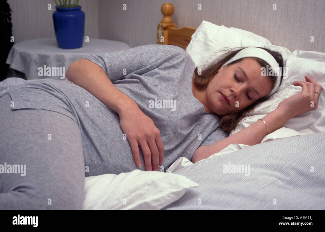 Teenager/young Woman in late pregnancy lying down on bed having rest Stock Photo