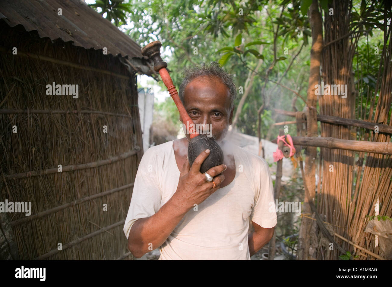 Man smoking from a homemade pipe in rural Bangladesh Stock Photo