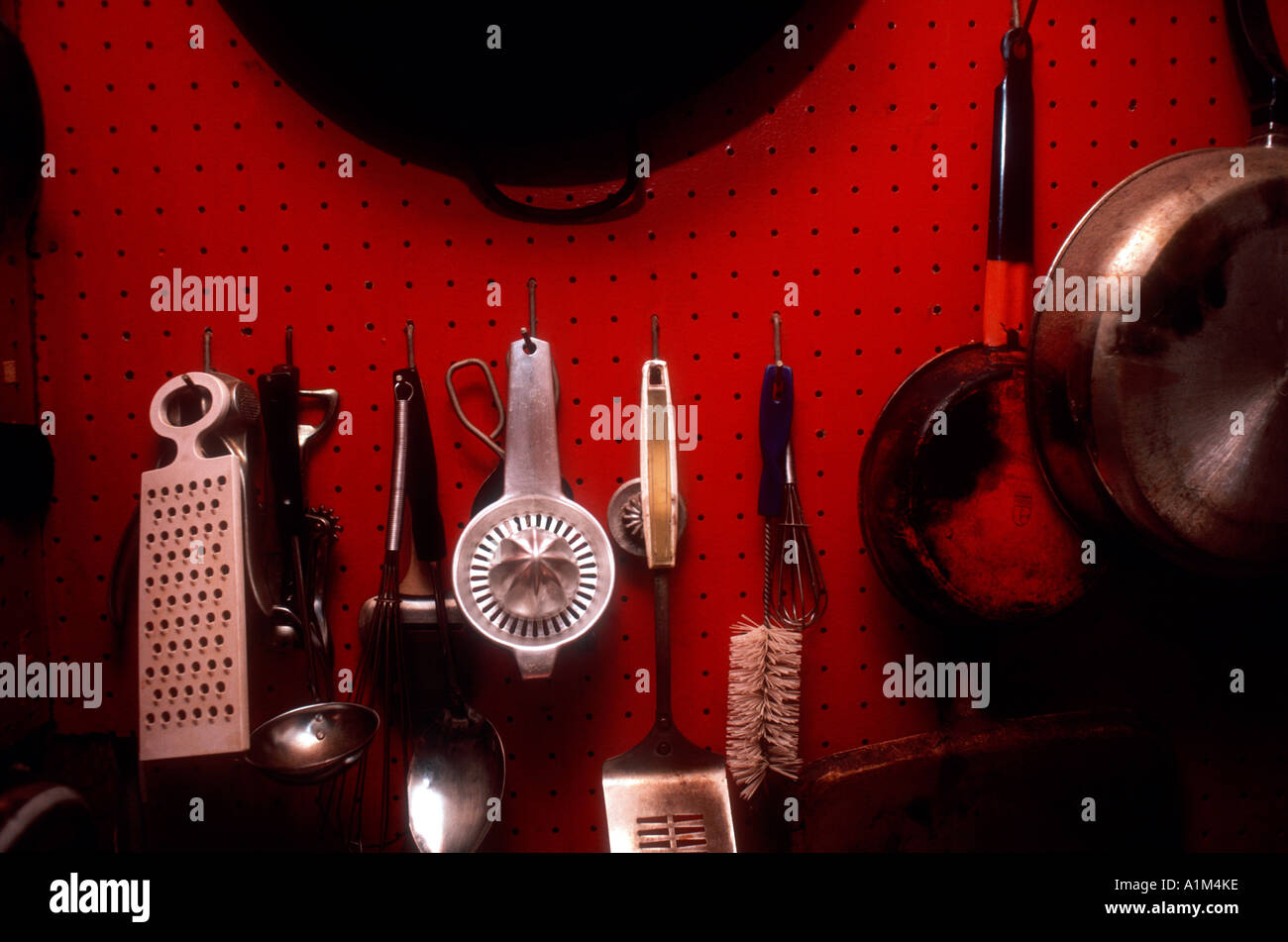 A collection of well used kitchen tools hanging from a pegboard Stock Photo Alamy
