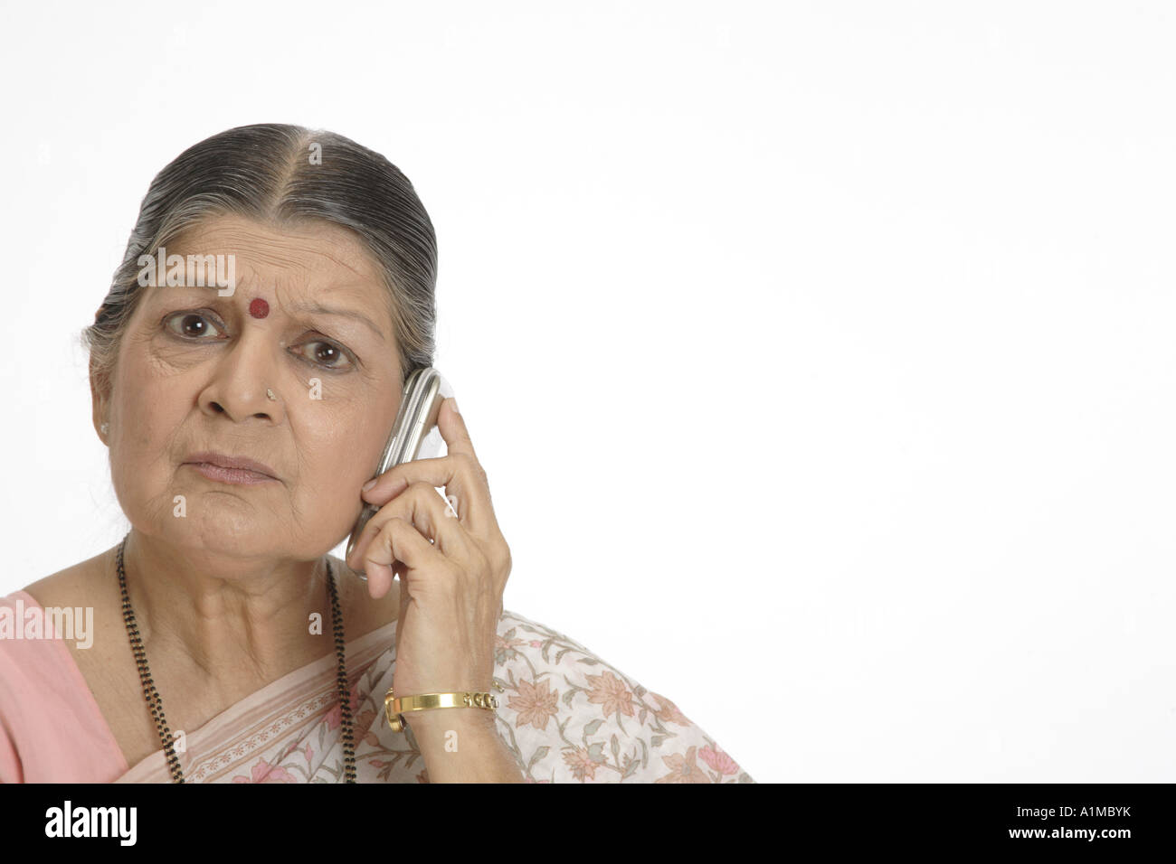 Indian senior citizen dot on forehead in sari talking on cellphone Stock Photo