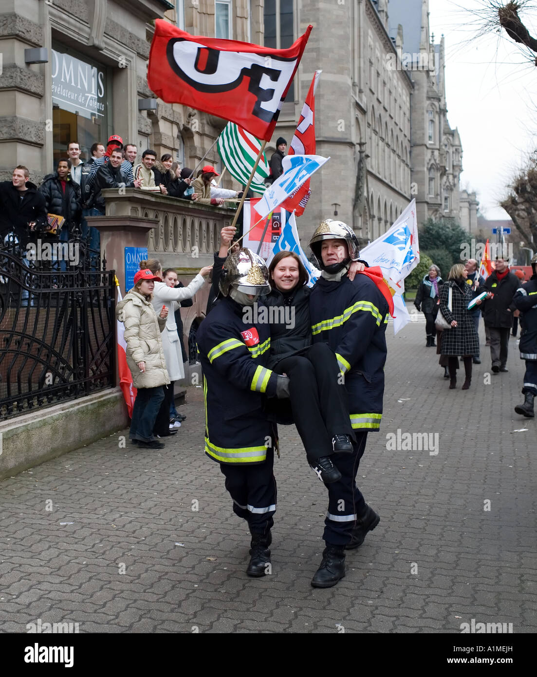 April 14 2006, 2 firemen carrying a protester girl holding a FO flag, protest march against Bolkestein directive, Strasbourg, Alsace, France, Europe Stock Photo