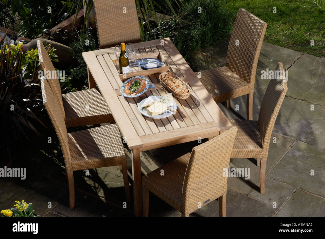 teak dining table chairs and lunch outside in the sunshine Stock Photo