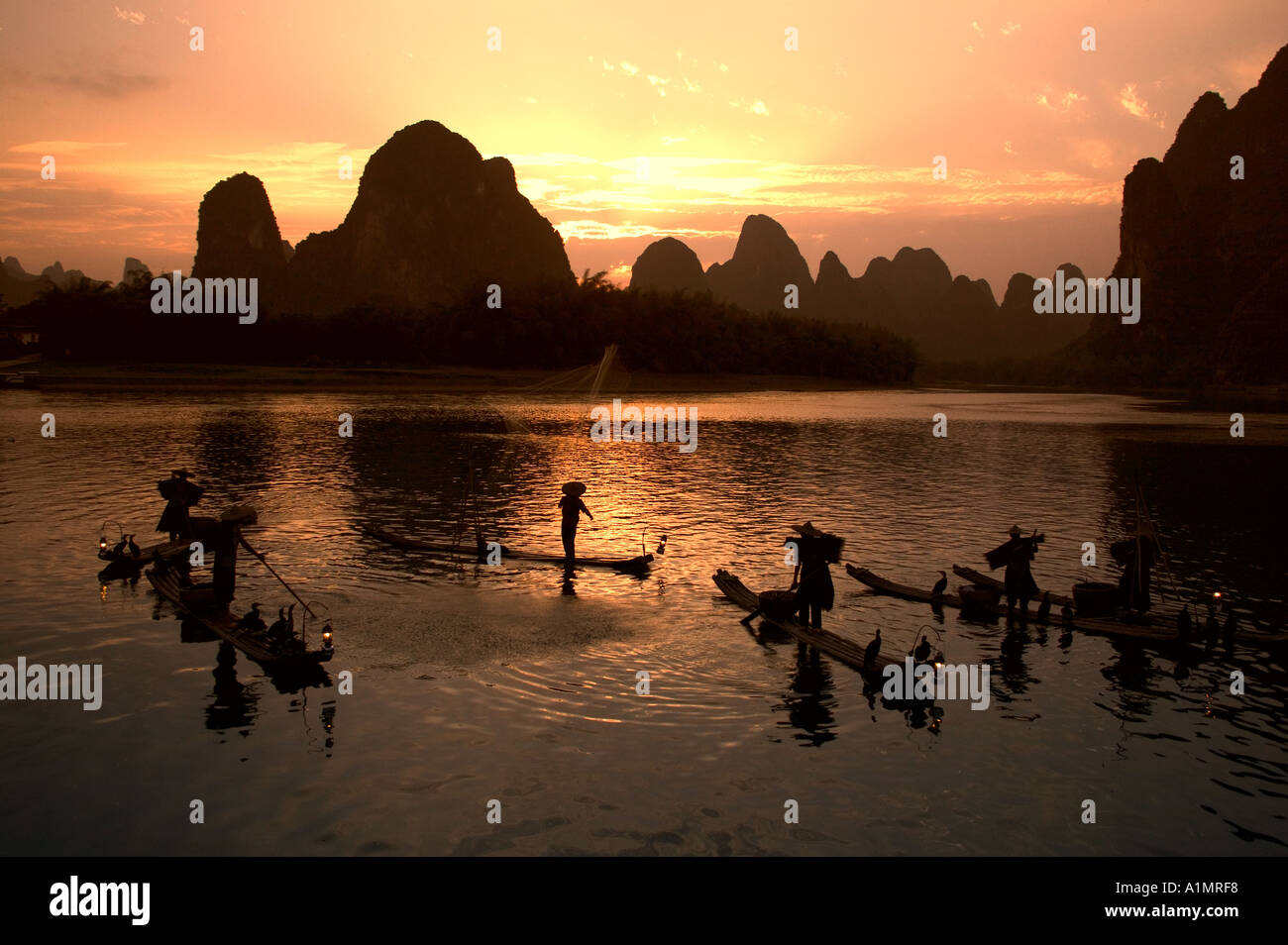 Fishermen on bamboo rafts on Li River at sunset Guangxi Province China Stock Photo