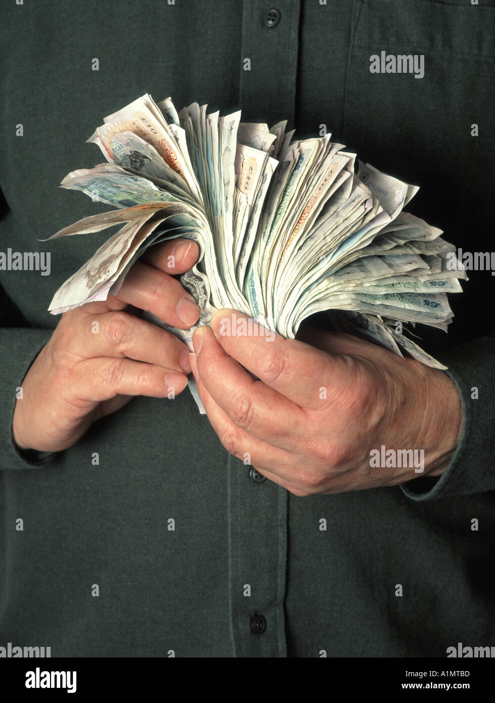 Close up business man two hands gripping hoarding & holding onto stacks of assorted cash in