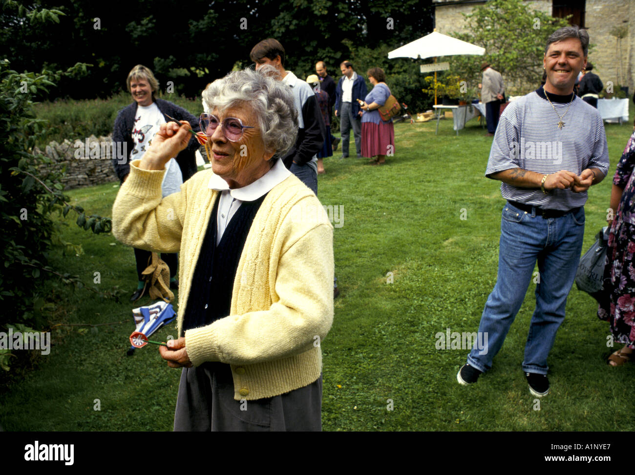 OLD LADY PLAYING DARTS IN GARDEN AT THE VILLAGE FETE. EAST LEACH