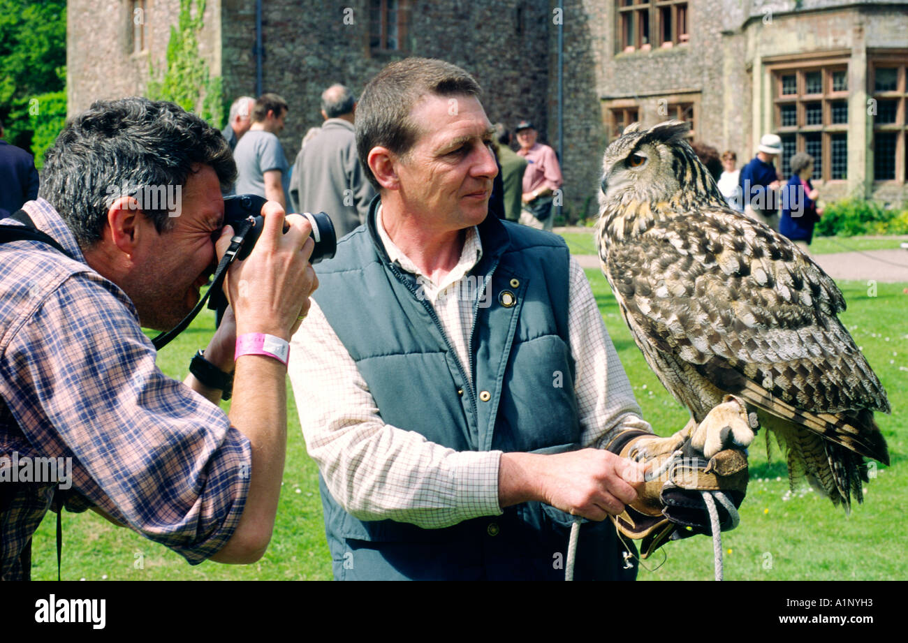 European Eagle Owl Bubo bubo with keeper being photographed by visitor to World Owl Centre at Muncaster Castle Cumbria England Stock Photo