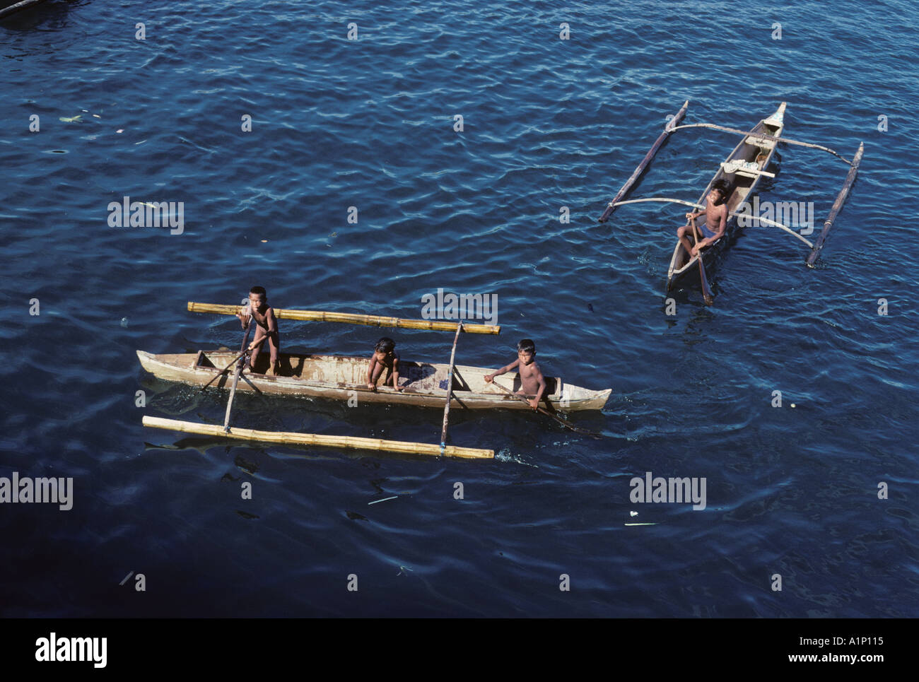 Badjao Tau Laut sea gypsies young boys in outrigger canoes Isabela harbour Basilan Strait Basilan Island Mindanao Philippine Stock Photo