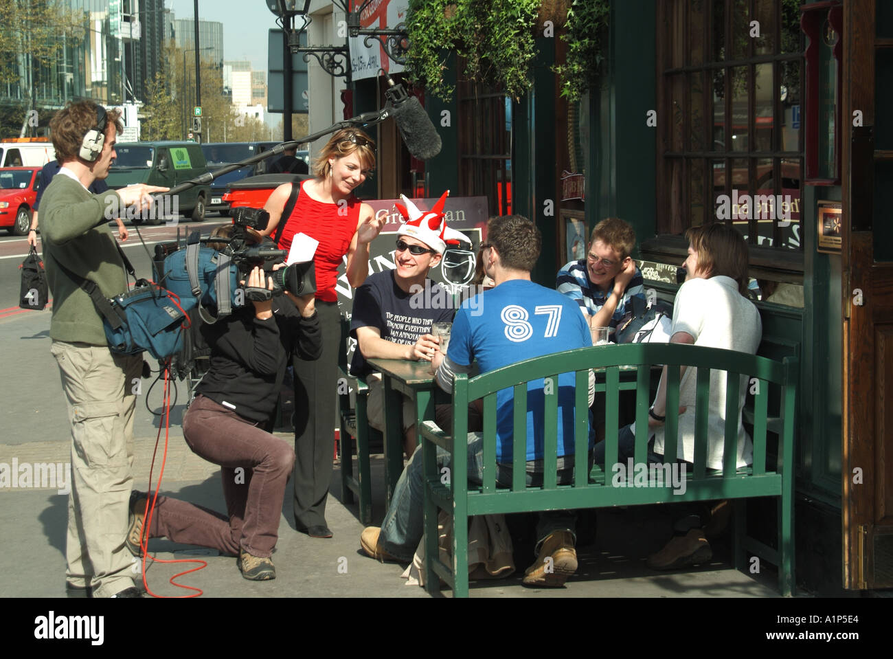 London youngsters at outdoor pub table being interviewed by video crew possibly for TV at time of football tournaments Stock Photo