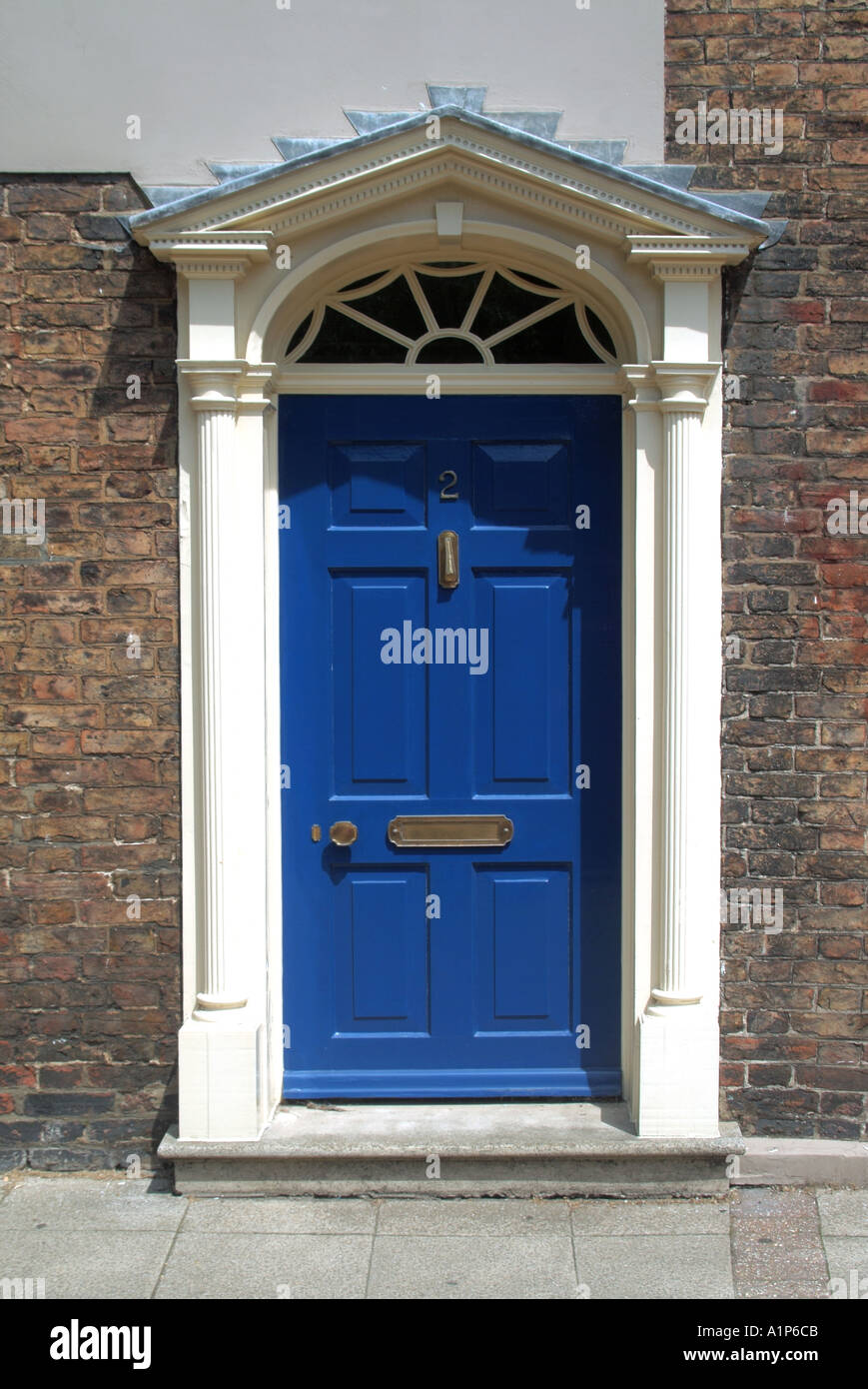 Blue residential front door with white surround opening directly onto pavement Stock Photo