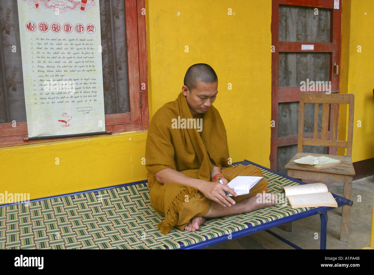 A Thai Buddhist monk reads in a book outside his monastery in Sarnath in Uttar Pradesh in India Stock Photo