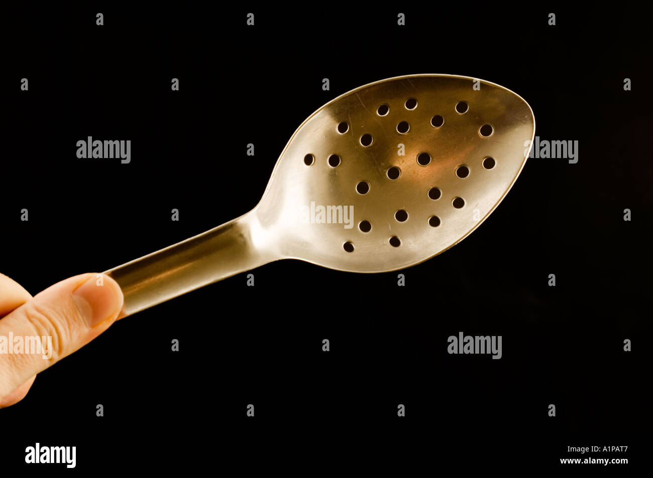 hand holding a metal draining spoon slotted spoon Stock Photo Alamy