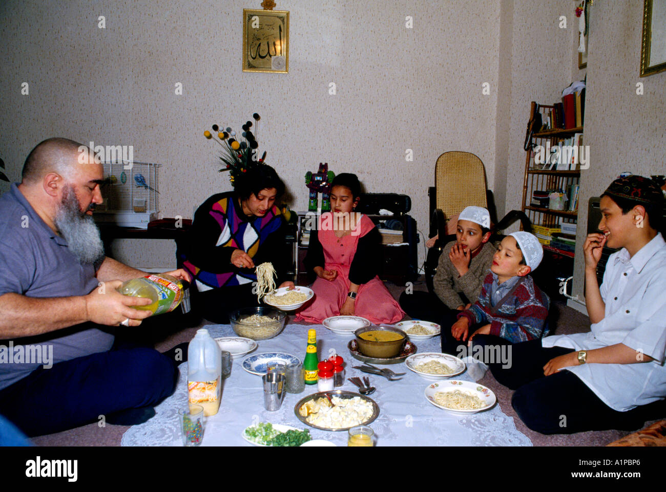 Clapton London Muslim Family Sitting on the Floor  Eating Meal Father Pouring Drink During Ramadam Stock Photo