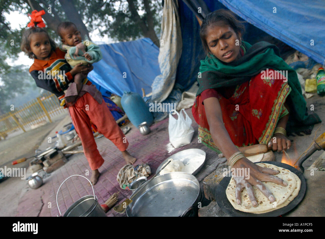 A women cooks food outside a tent in a slum dwelling in New Delhi in India Stock Photo
