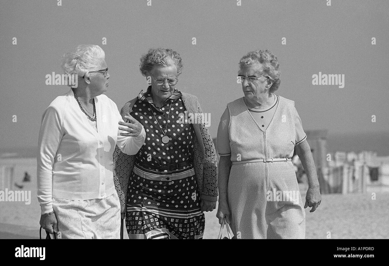 Three old ladies walking along a sea front talking. Stock Photo