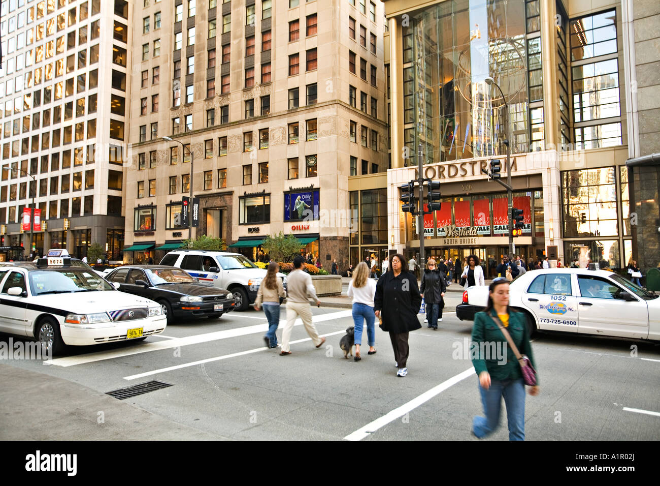 ILLINOIS Chicago Pedestrians cross Michigan Avenue in front of North Bridge and Nordstrom department store traffic on street Stock Photo