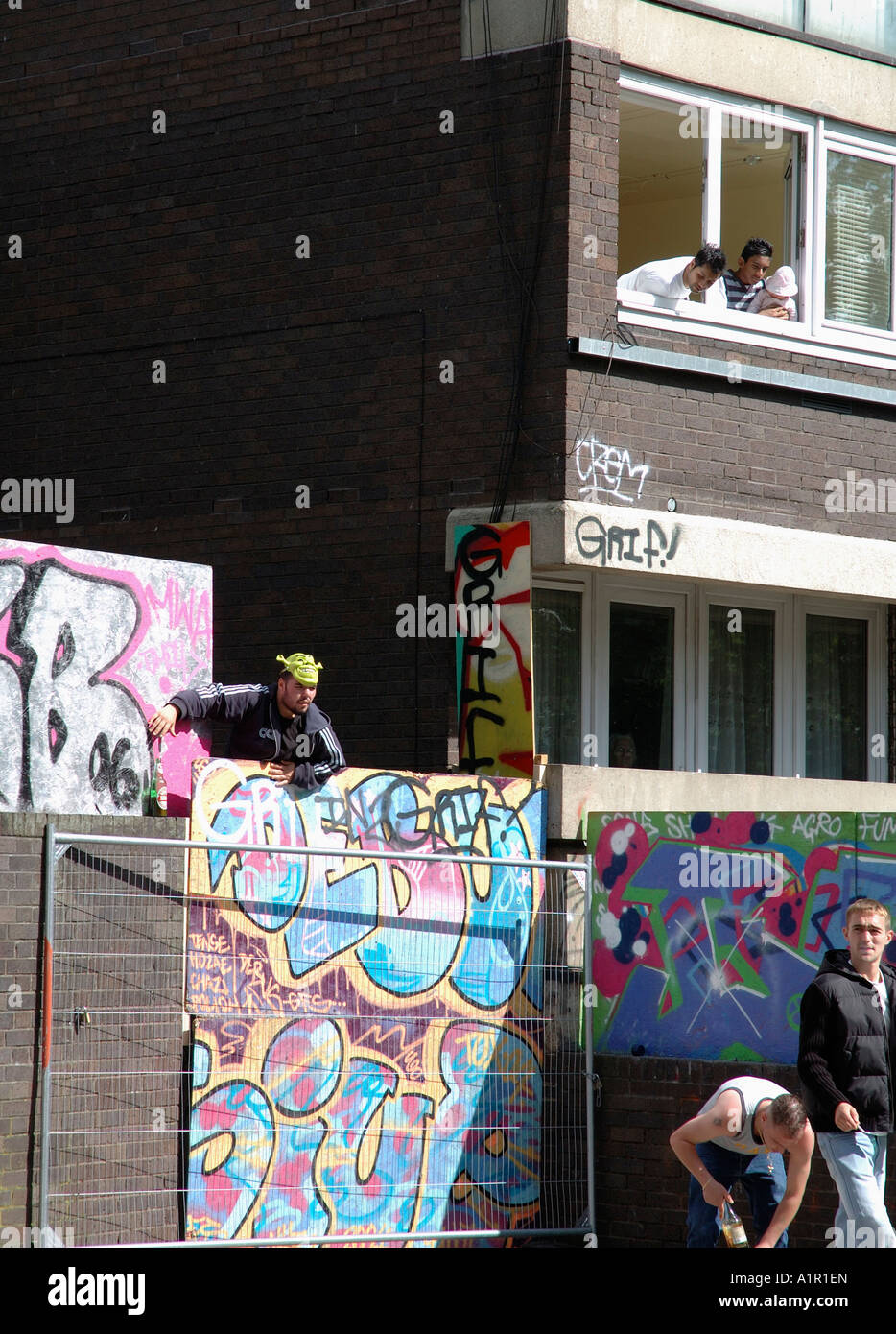 Youths up to no good escaping over wall in inner city housing estate. Stock Photo