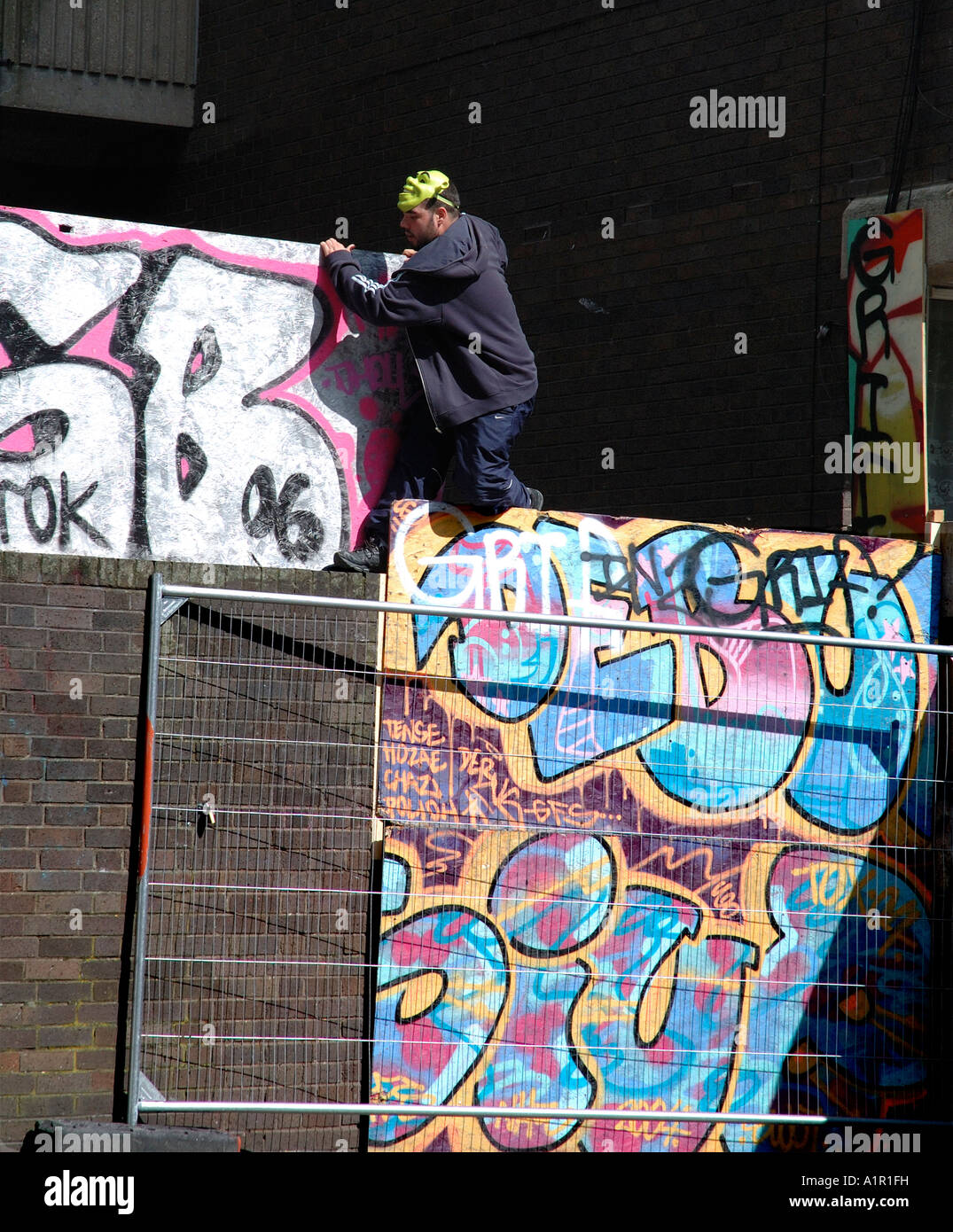 Youths up to no good escaping over wall in inner city housing estate. Stock Photo