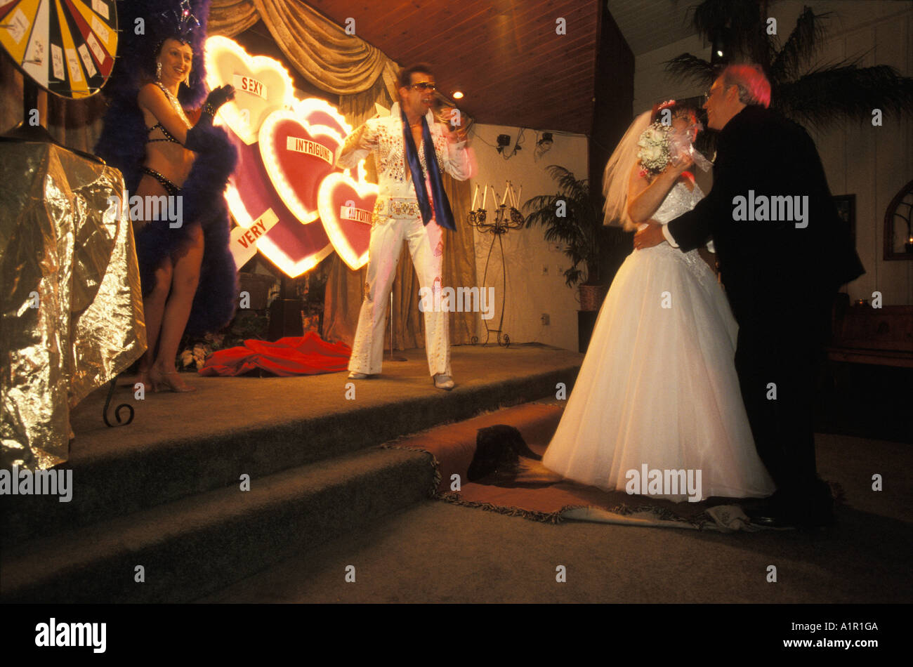 An Elvis impersonator sings for a newly wed  couple while they dance at their themed Elvis  wedding in Las Vegas Nevada USA Stock Photo