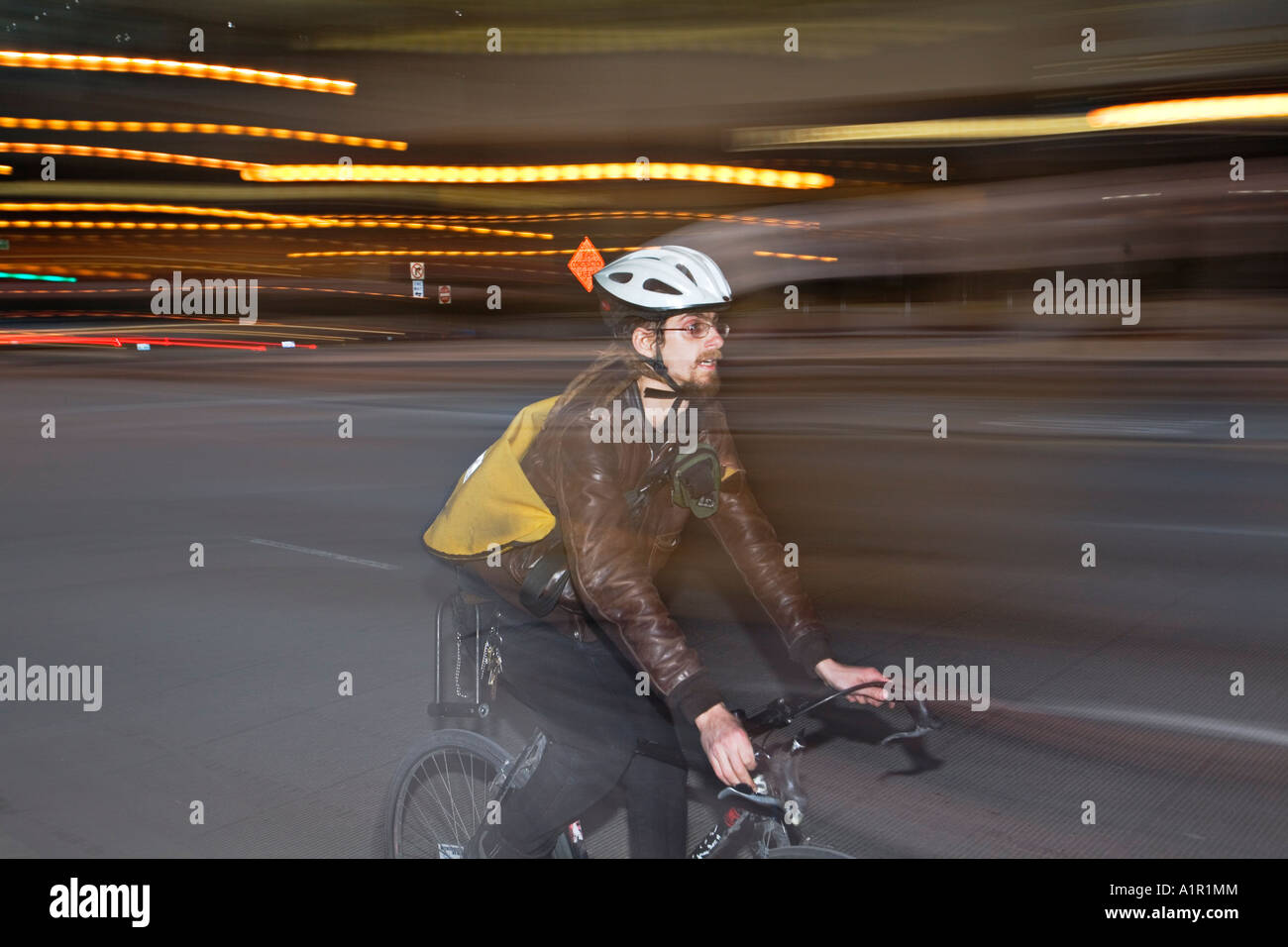 ILLINOIS Chicago Bicycle messenger wearing helmet on street at night
