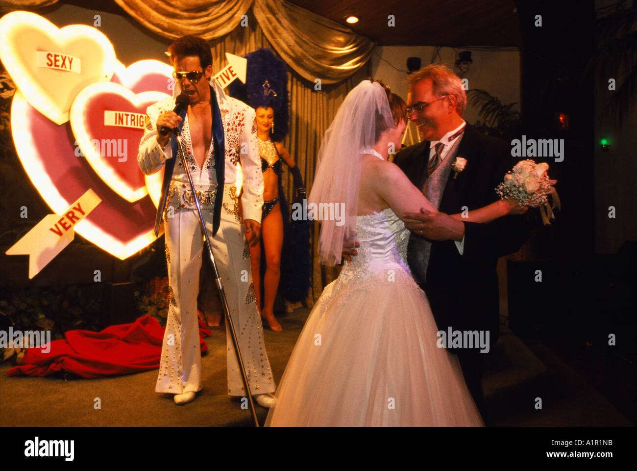 An Elvis impersonator sings for a newly wed  couple while they dance at their themed Elvis  wedding in Las Vegas Nevada USA Stock Photo