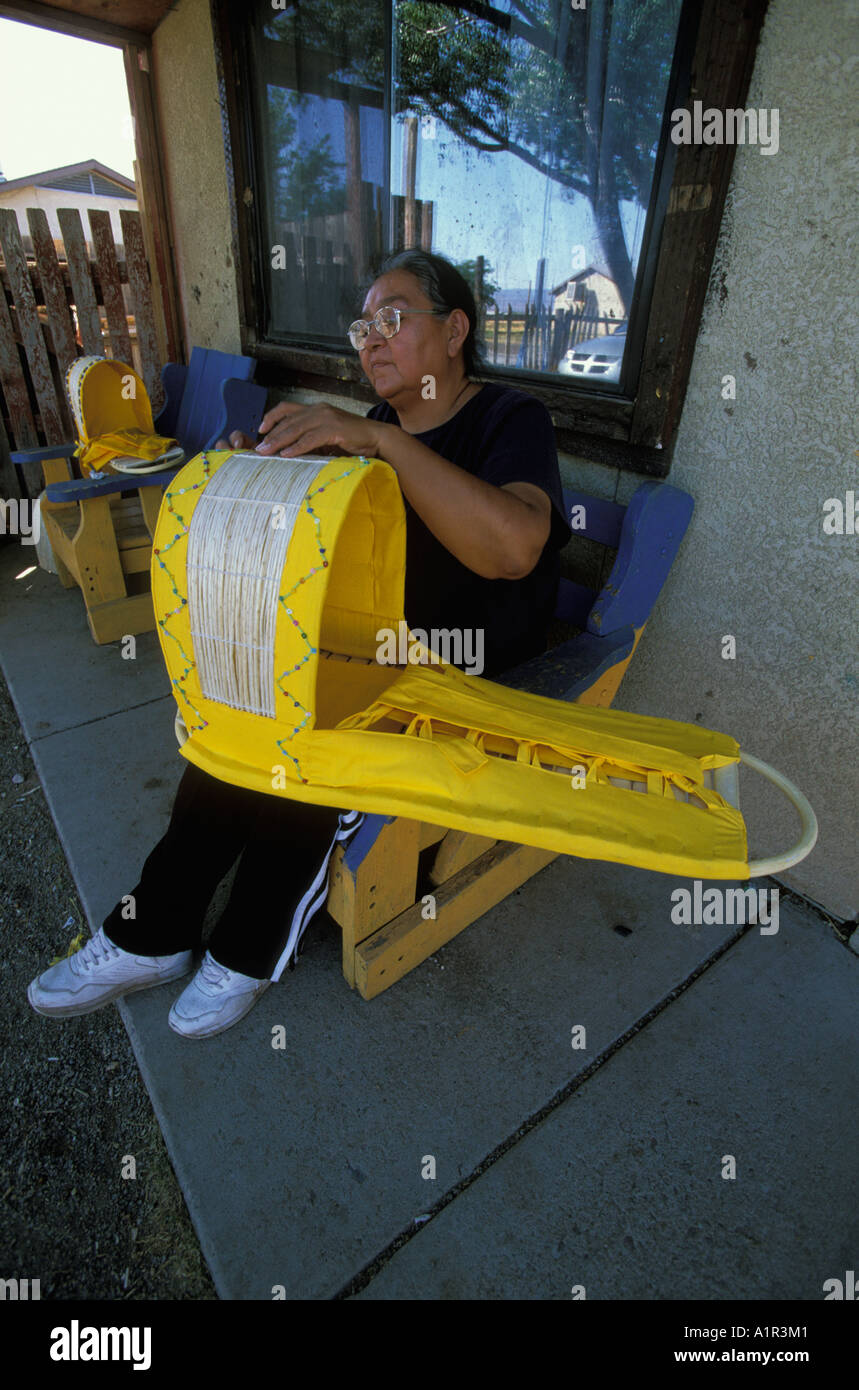 An Apache woman decorates a traditional baby cradle with beads on the