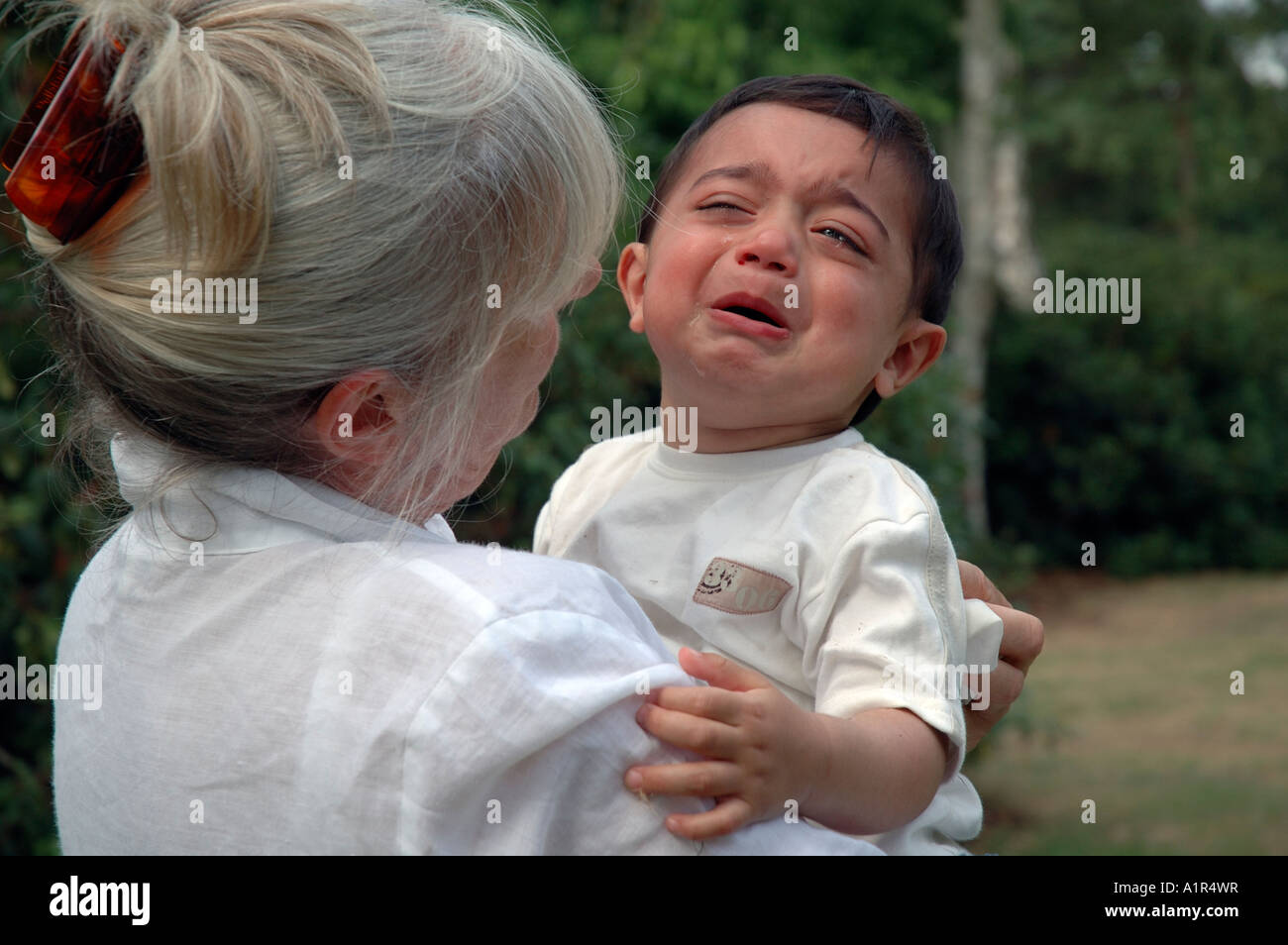 Grandmother comforting crying toddler. Stock Photo