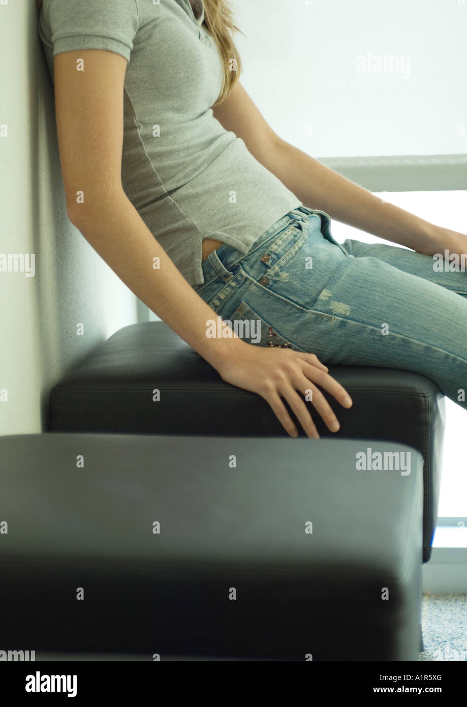 Young woman sitting on bench, mid section Stock Photo