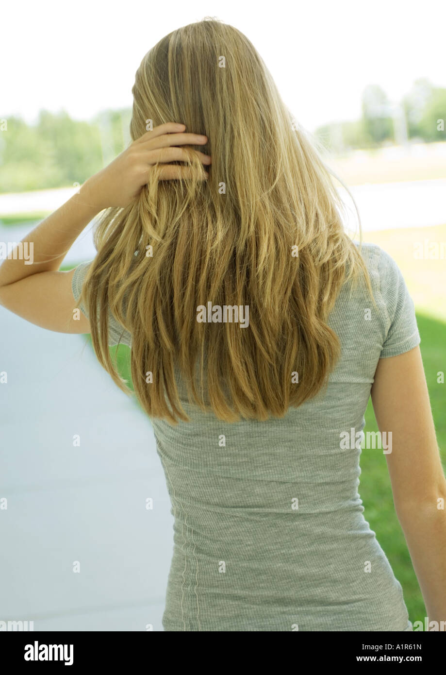 Young woman pushing hair back, rear view, waist up Stock Photo