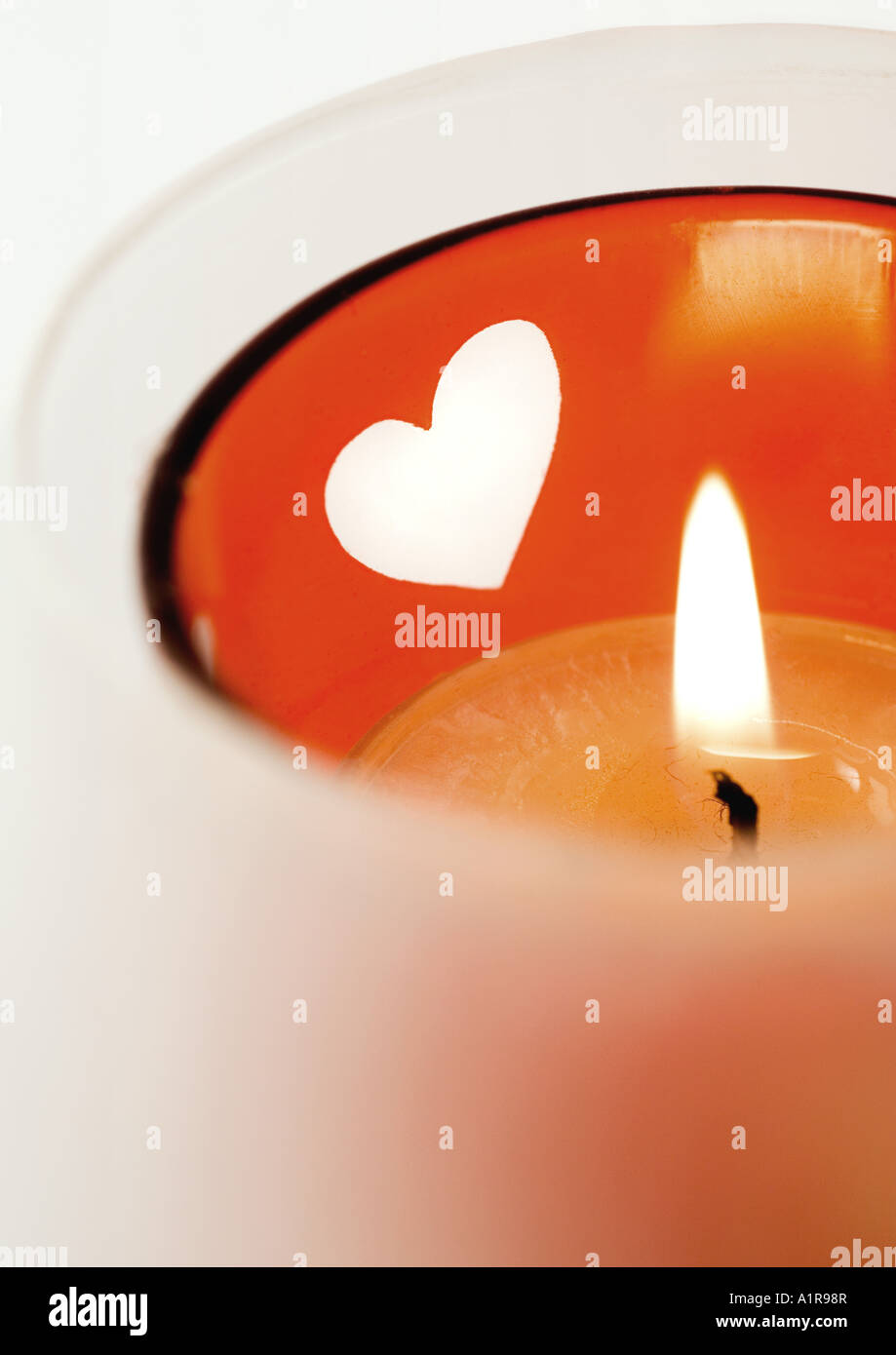 Lit candle in candleholder with heart pattern Stock Photo