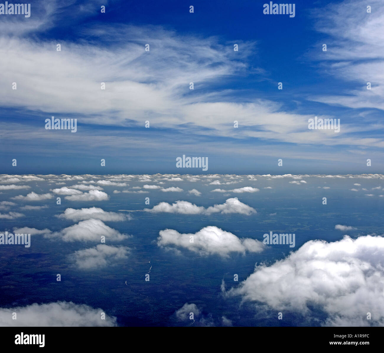 Aerial view above cumulus and below stratus cloud formations against blue sky Stock Photo