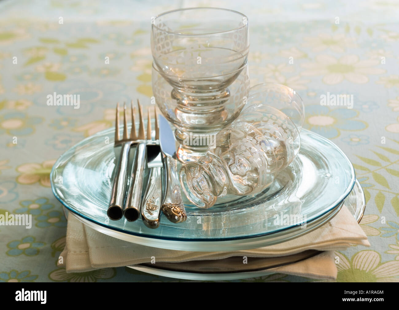 Stack of clean plates, napkins, silverware and glasses Stock Photo