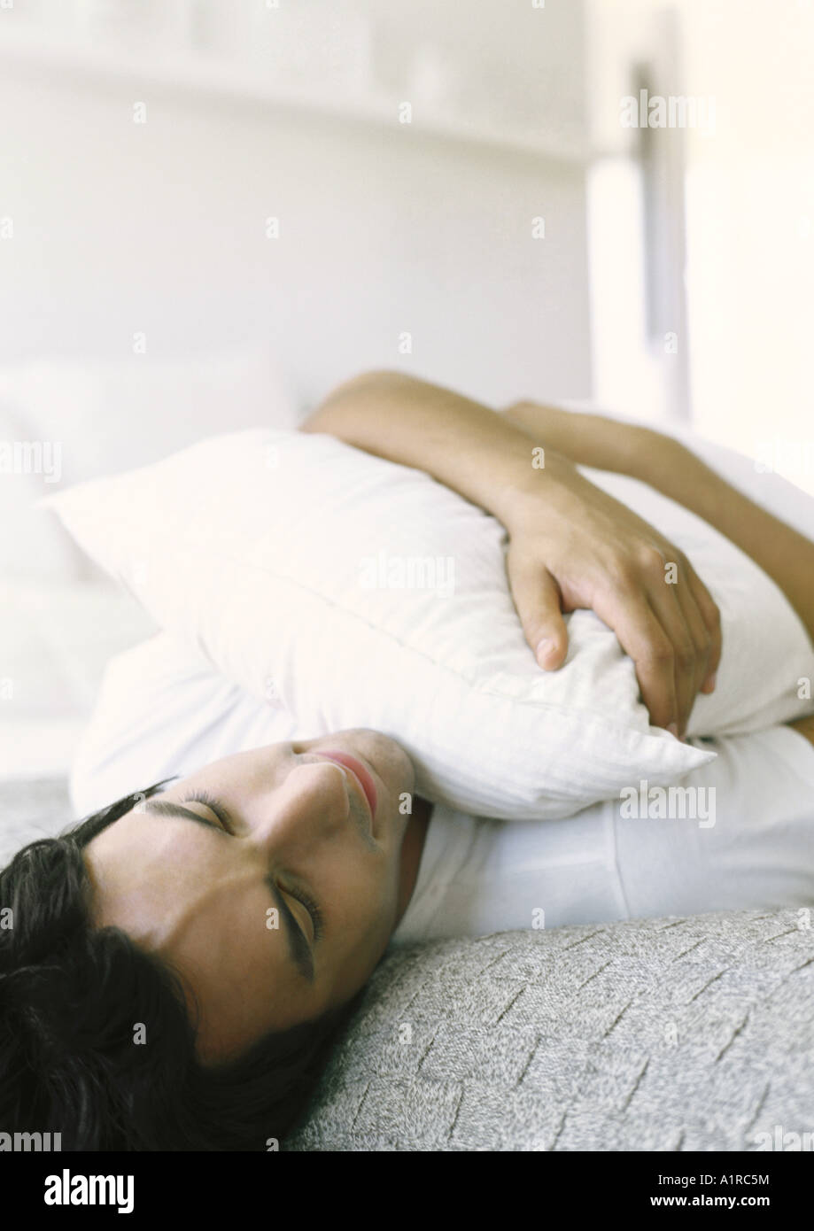 Man lying down, holding pillow Stock Photo