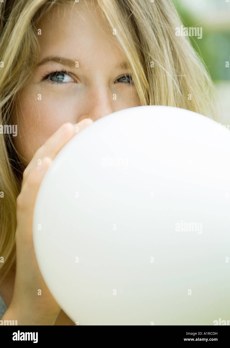 Young woman blowing up balloon Stock Photo