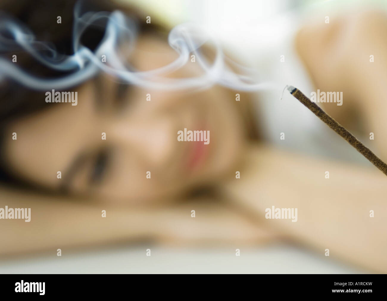Woman watching incense burn Stock Photo