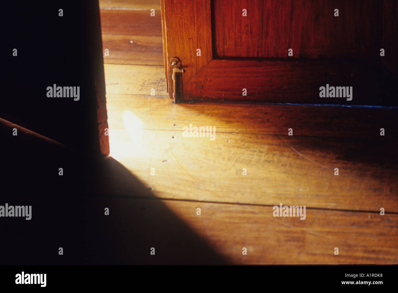 An antique door is ajar letting light define the different dimensions