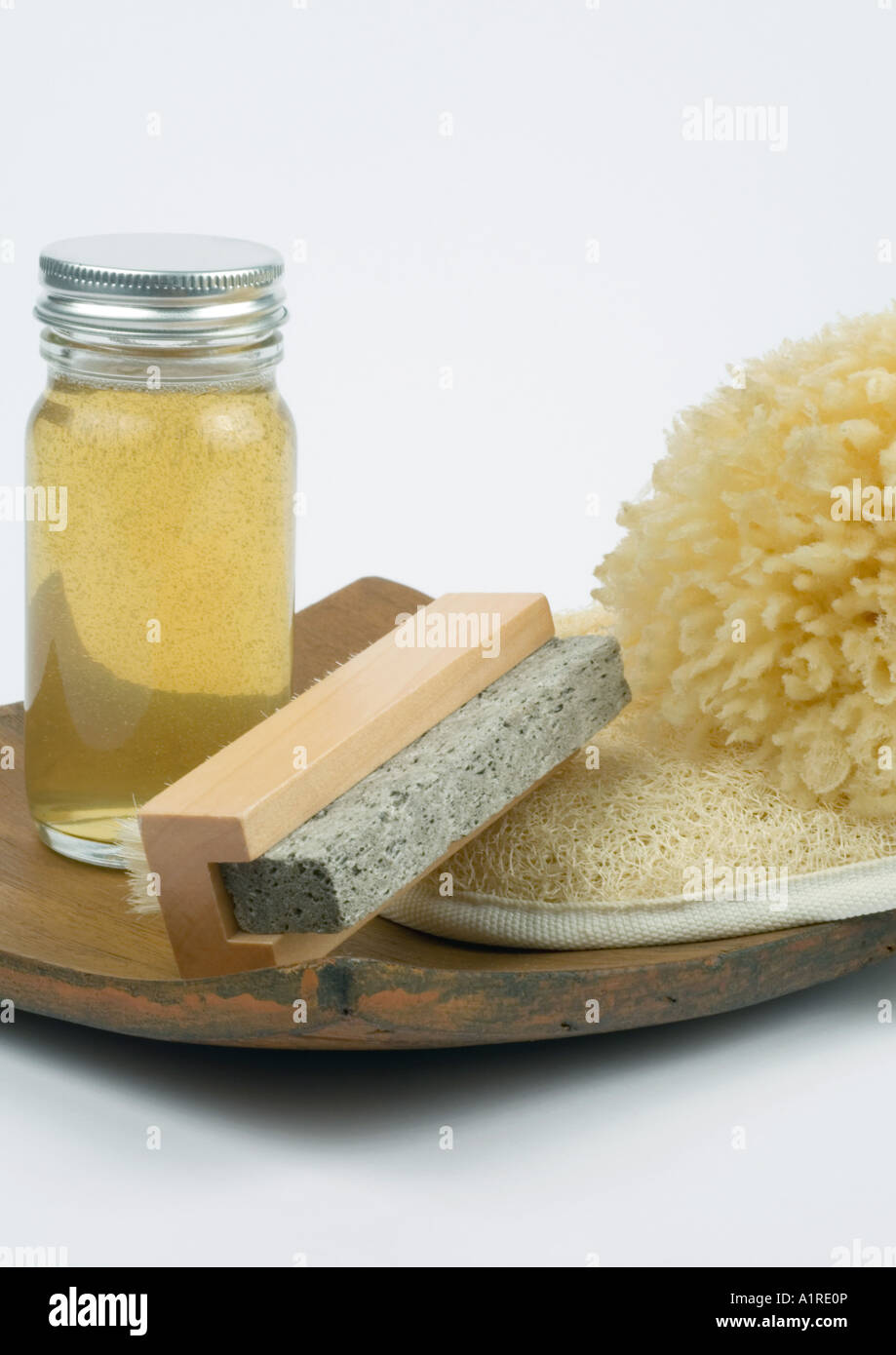 Grooming products, pumice stone, body oil, loofah and sponge on wooden tray Stock Photo