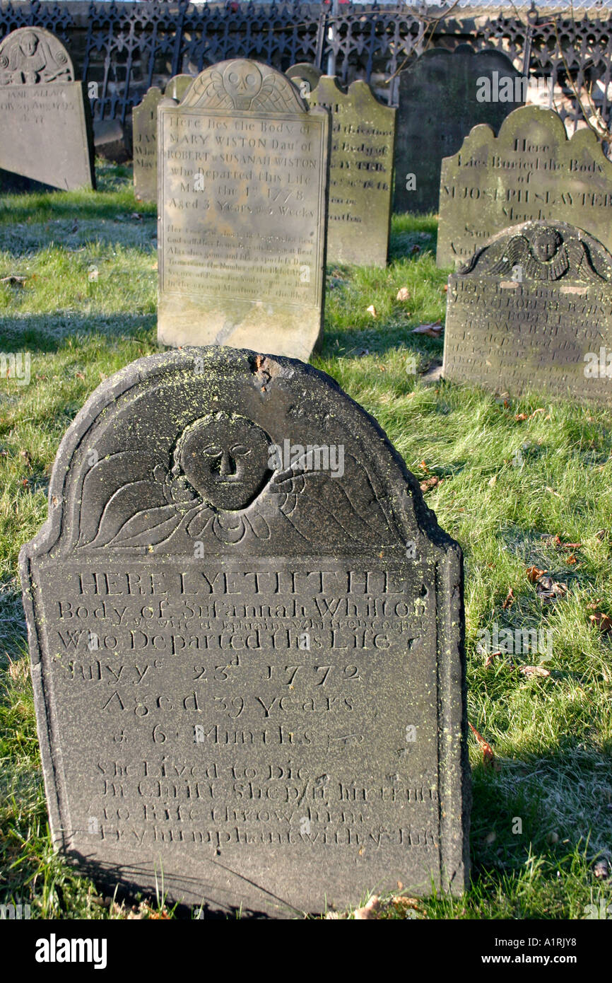 Old dark grey carved stone grave markers on a frosty sunny morning Old
